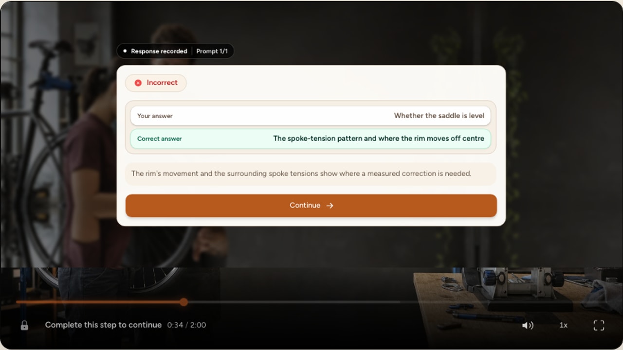 A real Interakly video question centered over a bicycle repair lesson and showing corrective feedback after a wrong answer